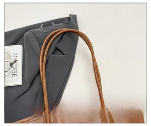 Detail view of double slim shoulder straps on vintage brown leather tote bag with stitching