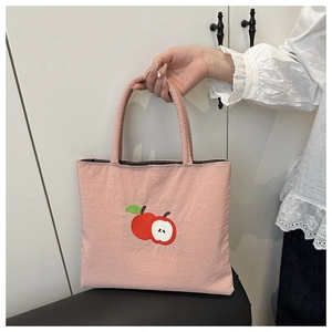 Close-up of pink nylon tote bag with detailed red apple embroidery and fabric texture