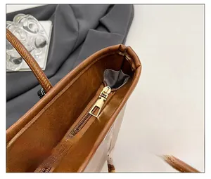 Detail of smooth gold zipper and leather texture on a brown large-capacity tote bag