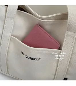 Detail view of canvas tote front pocket with BE YOURSELF print and pink card holder