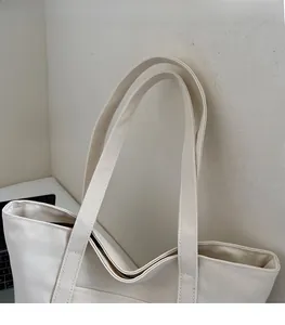 Detail view of reinforced canvas tote shoulder straps and smooth zipper closure