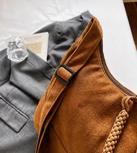 Detail of adjustable strap and woven zipper on brown suede large hobo bag