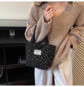 Close-up of black canvas tote bag featuring printed white bows and heart patterns