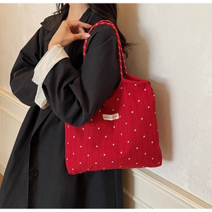 Detail of red canvas tote bag with star pattern and woven strap on a model shoulder