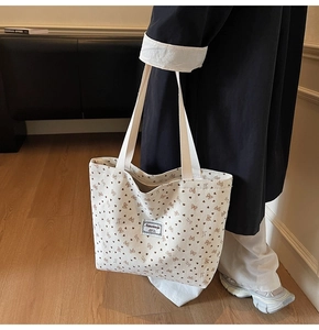 Detail of cream corduroy tote bag featuring butterfly patterns and textured stripes