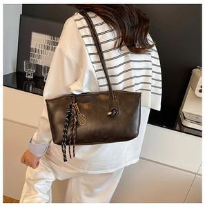Detail of dark brown leather tote bag with tennis racket charm and striped ribbon