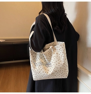 Detail view of large corduroy tote bag with heart and bow patterns in off-white