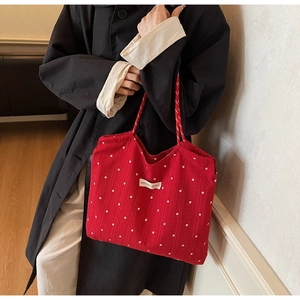 Close-up of red canvas tote bag with white floral pattern and woven handle detail