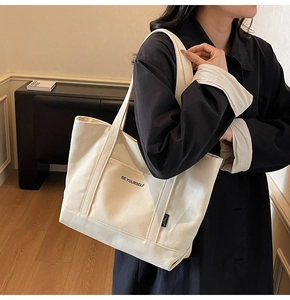 Detail of minimalist canvas tote bag with Be Yourself print and decorative front pocket