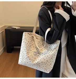 Close-up of white corduroy tote bag featuring brown heart and bow patterns