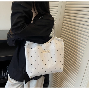 Detail of white floral canvas tote bag with shoulder strap and black brand label