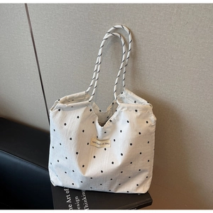 Close-up of cream canvas tote bag with black floral pattern and twisted rope straps