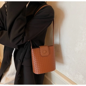 Detailed view of brown woven bucket bag featuring premium leather texture and flap closure