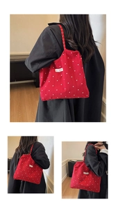 Detail of red floral canvas tote bag with striped shoulder straps and brand label