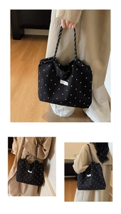 Detail of black canvas tote bag with floral pattern and striped handles on a model