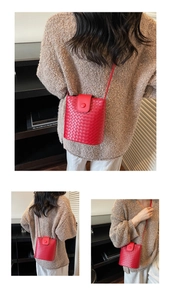 Detail of red woven leather bucket bag featuring a button flap and slim shoulder strap