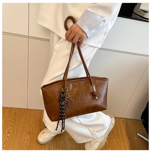 Brown retro tote bag detail with golden tennis racket pendant and woven tassels