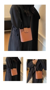 Detail of a brown woven crossbody bag with a magnetic snap and fine adjustable strap