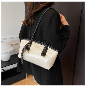 Close-up of a cream tote bag with black trim and a checkered scarf on a model