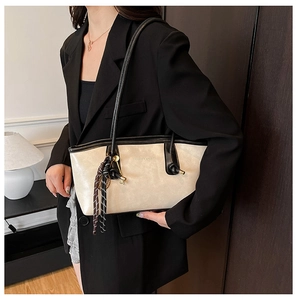 Chic cream tote bag with black strap and striped tassel detail shown on model