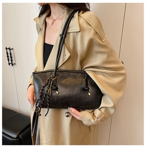Close-up of black retro leather tote bag with fine stitching and woven charm detail