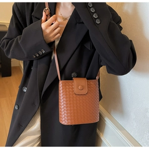 Close-up of brown woven texture bucket bag with adjustable strap on a female model