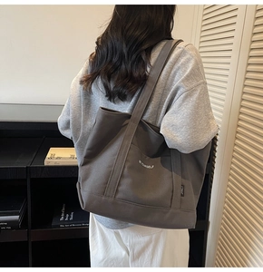 Detail of dark grey canvas tote bag with BE YOURSELF print worn over the shoulder