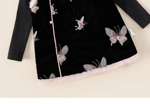Detailed view of pink faux fur trim and purple butterfly embroidery on black velvet dress