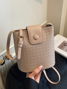 Minimalist beige woven leather bucket bag for women with crossbody strap and gold button