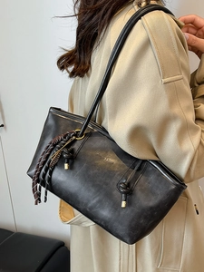 Chic black matte oversized hobo bag with knotted strap and fringe tassel on a model