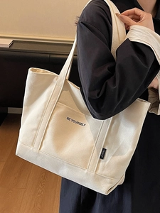 Minimalist canvas tote bag with BE YOURSELF print and wide shoulder straps on model