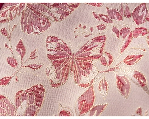 Dettaglio del tessuto jacquard rosa con farfalle rosse e fili dorati