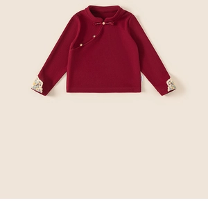 Dettaglio di maglia rossa stile cinese per bambini con ricami floreali e bottone a nodo