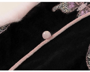 Detail of girls' black velvet coat with pink faux fur collar and butterfly embroidery