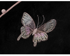 Macro detail of refined butterfly embroidery on black velvet fabric with pink bead accent