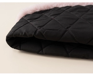 Detailed close-up of black quilted fabric with elegant pink faux fur trim on girl's outfit