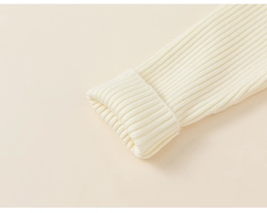 Close-up of ribbed knit cuffs on cream winter outfit for girls with soft texture