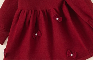 Détails de robe en tricot rouge avec nœuds décoratifs, perles et poignets côtelés