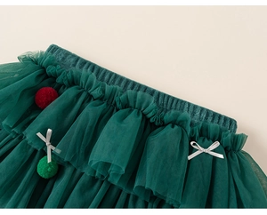Détail d'une jupe tutu en tulle vert avec pompons festifs et nœud sur la taille élastique