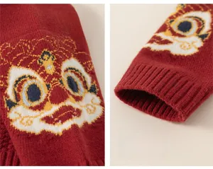 Détail d'un pull en maille rouge festif avec motif lion et poignets côtelés