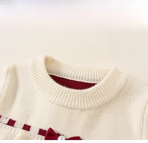 Détail du col de robe en tricot avec nœud rouge, perle et motif à carreaux