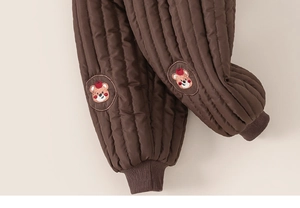 Détail du tissu matelassé et broderie d'ours sur pantalon marron pour enfants