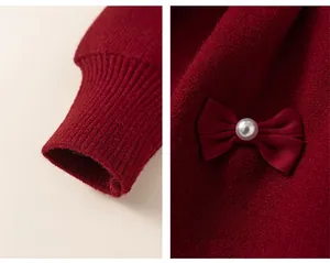 Détail de robe en tricot rouge montrant des poignets élastiques et nœud avec perle