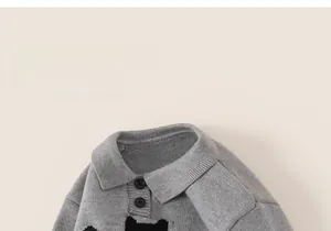 Detail of grey knitted kids sweater featuring a polo collar and cute cartoon cat pattern