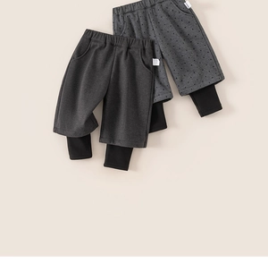 Detail of elastic waist and layered hem on girls' grey polka dot fake two-piece trousers