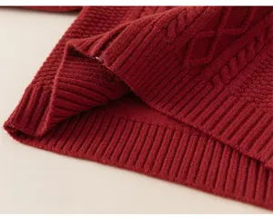 Gros plan d'un pull en maille torsadée bordeaux avec ourlet côtelé épais et texture
