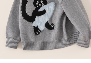 Detail of grey knitted sweater showing intarsia cat motif and ribbed cuffs texture