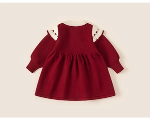 Détails de tricot côtelé et volants crème sur une robe en maille rouge pour fillette