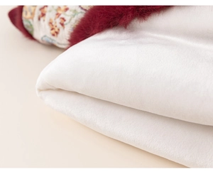 Close-up of white plush fabric with burgundy faux fur trim and ethnic embroidery