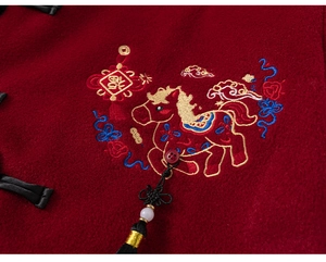 Detail of red wool fabric with golden horse embroidery and traditional knots on boy outfit